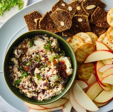 a platter featuring a green bowl of spread accompanied by crackers apple slices and a small dish of chopped green onions a platter featuring a green bowl of spread accompanied by crackers apple slices and a small dish of chopped green onions