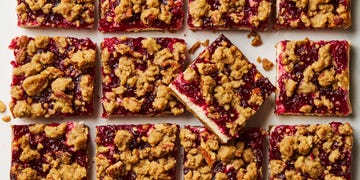 cheesecake bars topped with a layer of cranberries and a pecan crumble topping