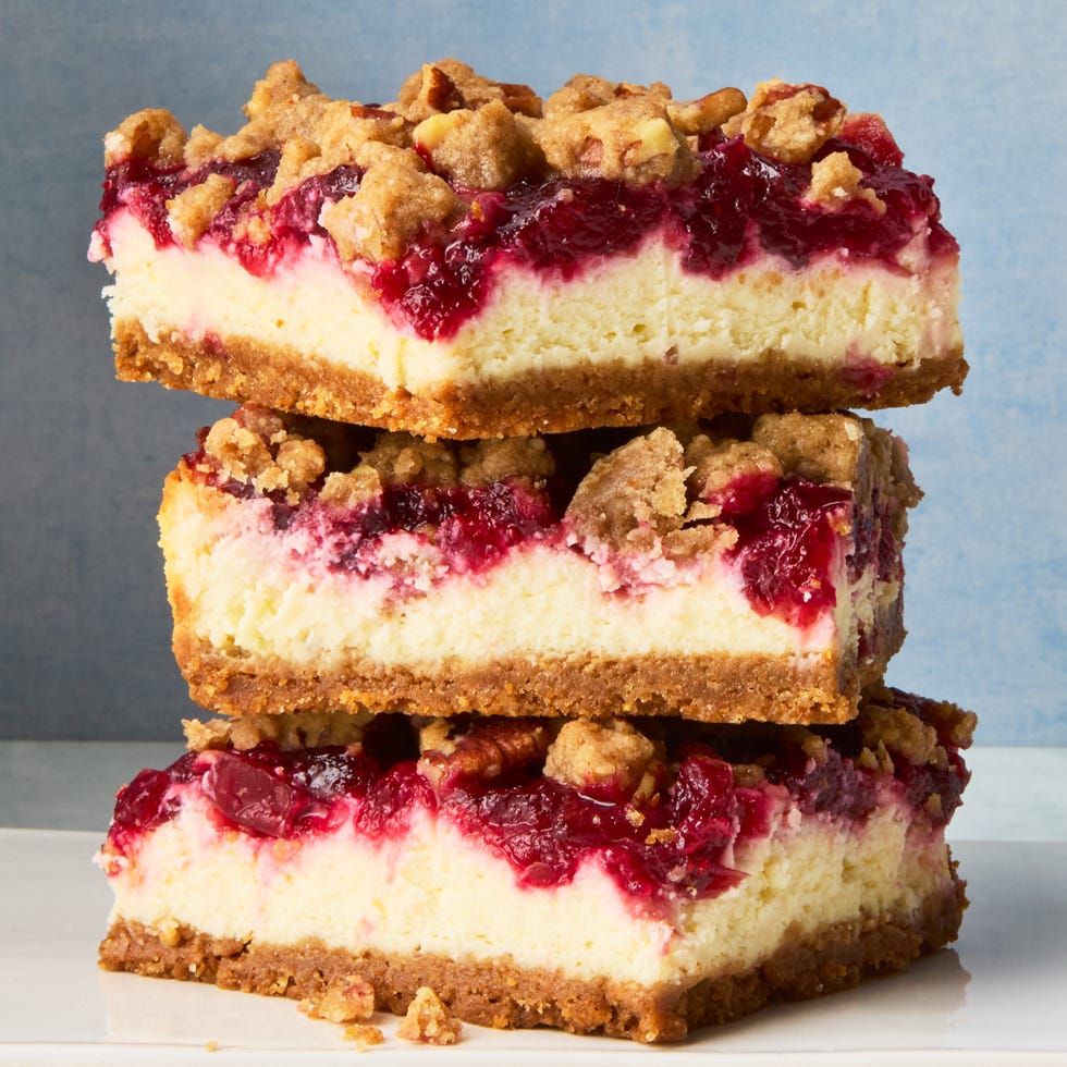 cheesecake bars topped with a layer of cranberries and a pecan crumble topping