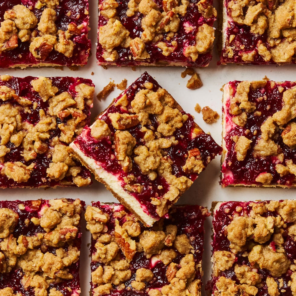 cheesecake bars topped with a layer of cranberries and a pecan crumble topping