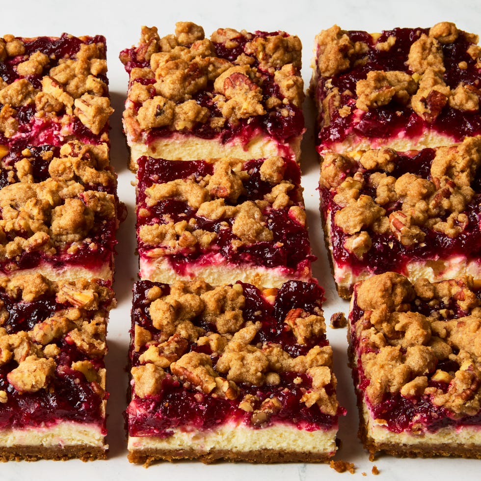 cheesecake bars topped with a layer of cranberries and a pecan crumble topping