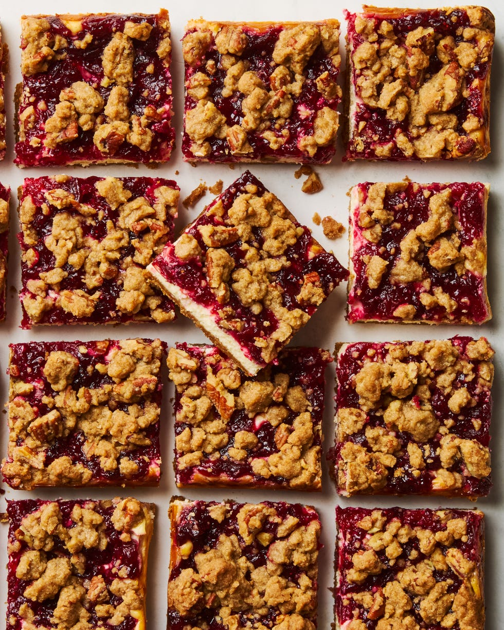 cheesecake bars topped with a layer of cranberries and a pecan crumble topping