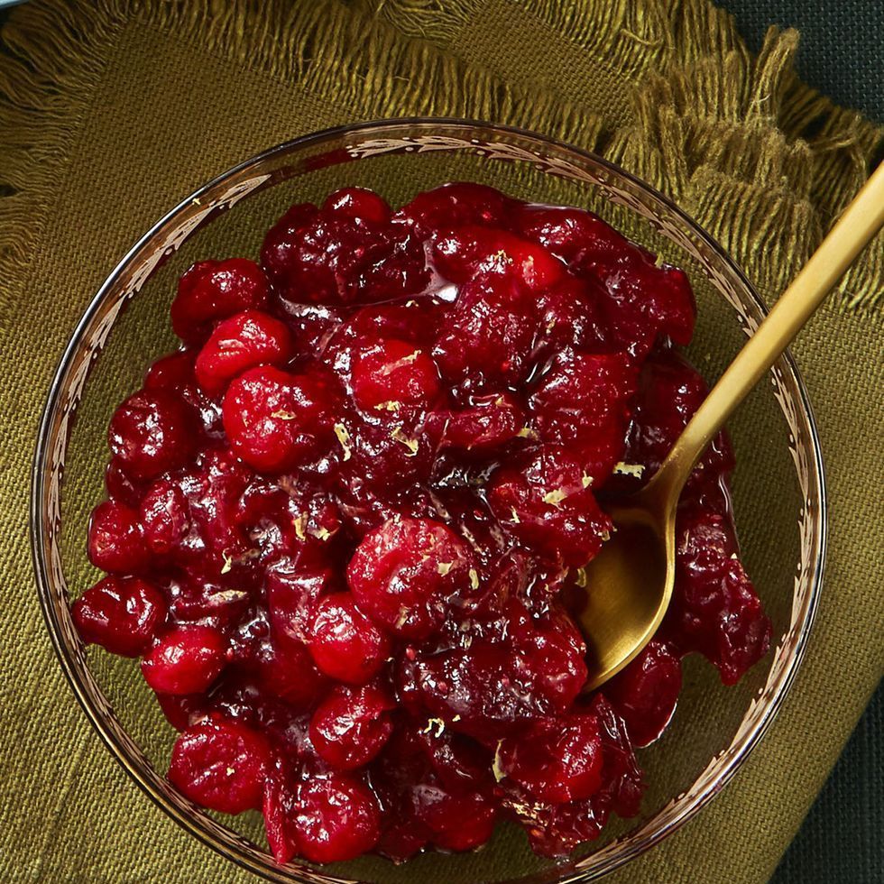christmas foods orange cranberry compote with a gold spoon on a green background