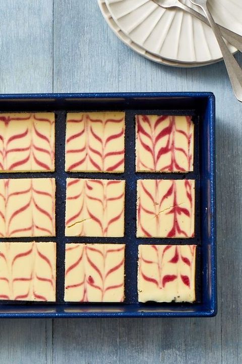 cranberry swirl cheesecake bars in a blue pan on a wooden table