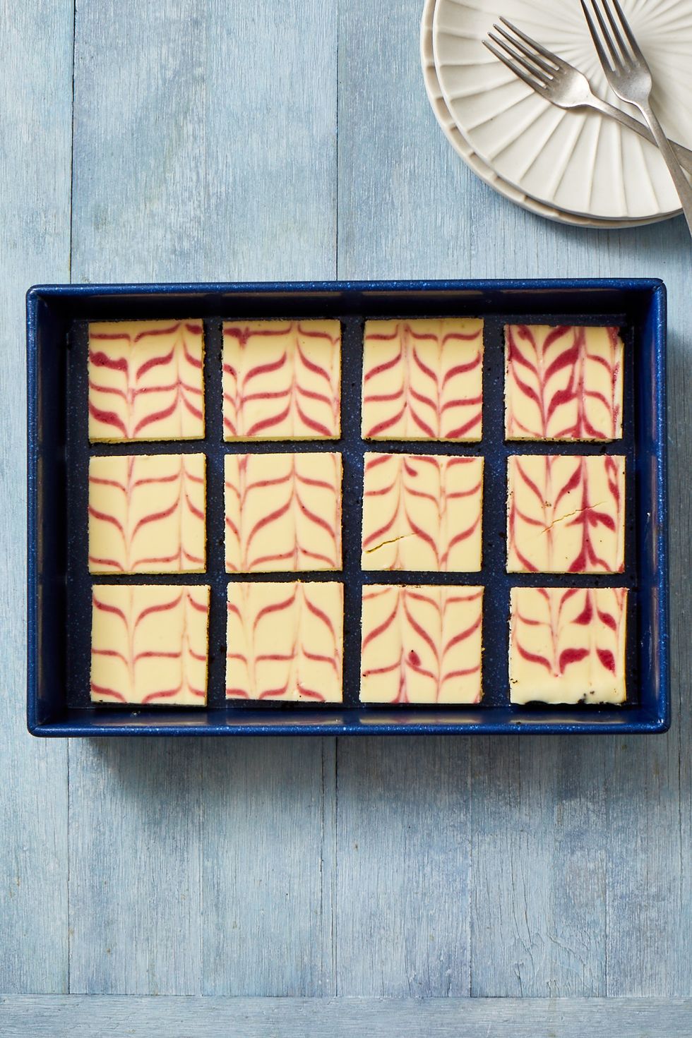 cranberry swirl cheesecake bars in a blue baking dish
