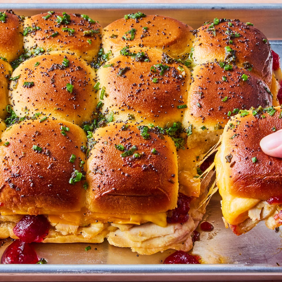 sliders filled with sliced turkey, cranberry sauce, and cheese topped with a poppyseed butter topping
