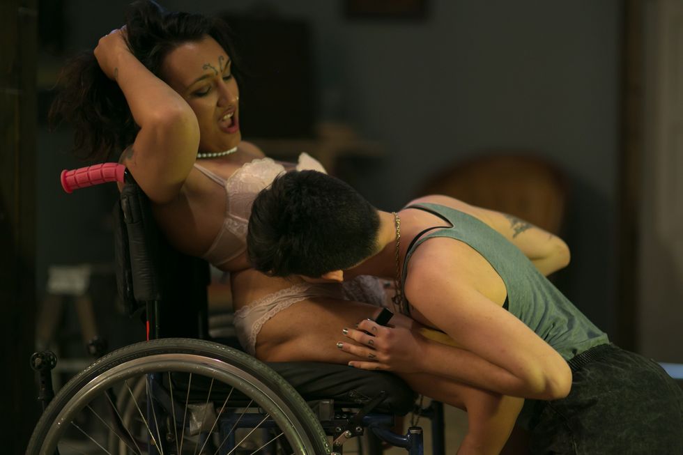 a kneeling porn performer kisses the stomach of a porn performer in a wheelchair