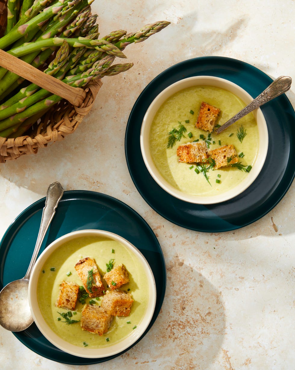 bowls of cream of asparagus soup with parmesan croutons with spoons