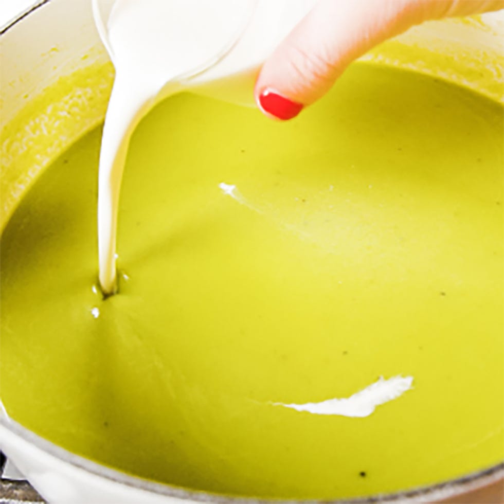 pouring cream into a green soup