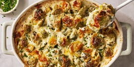 cheesy, bubbling creamed brussels sprouts in a white oval casserole dish