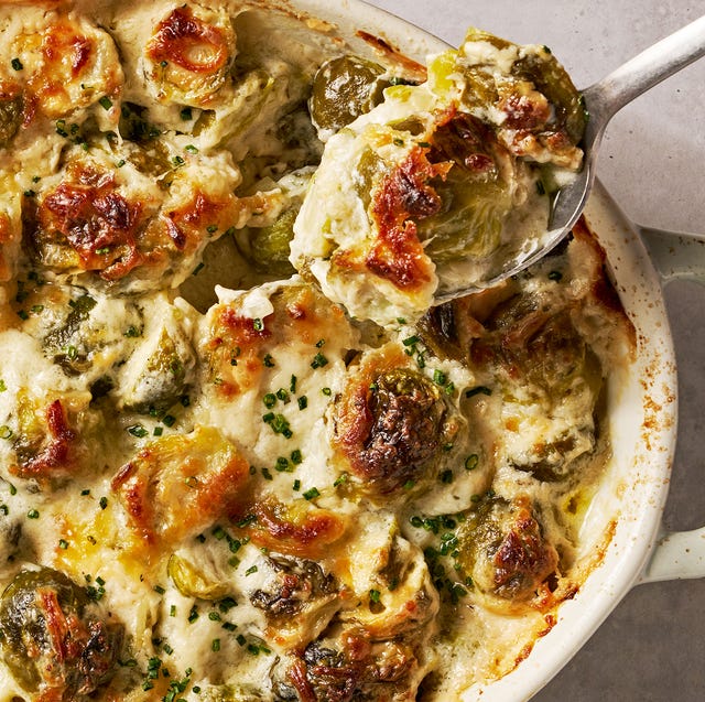 cheesy, bubbling creamed brussels sprouts in a white oval casserole dish