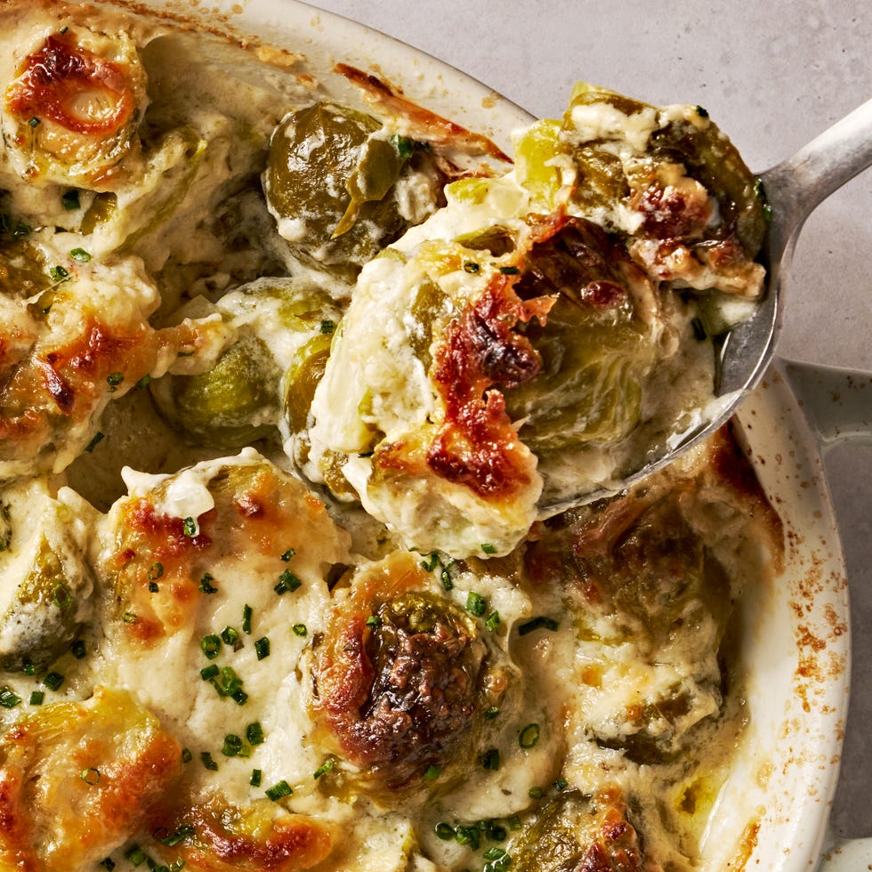 cheesy, bubbling creamed brussels sprouts in a white oval casserole dish