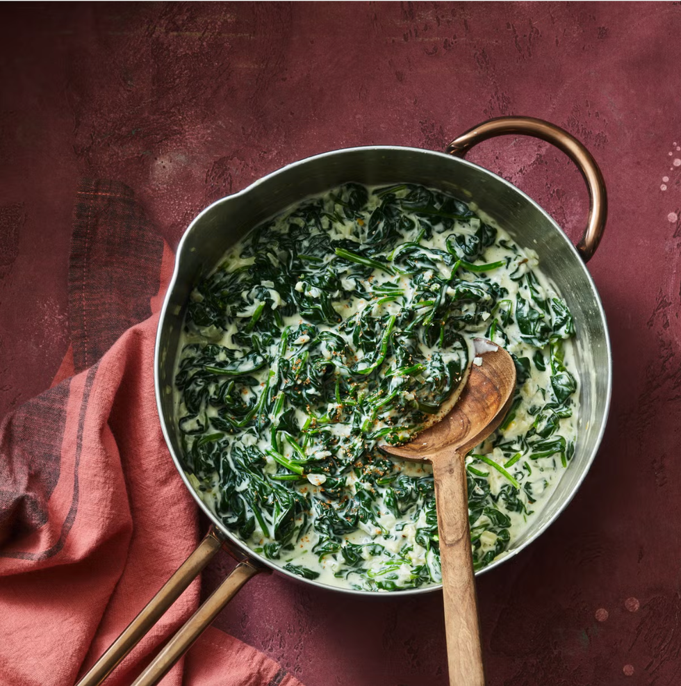 creamed spinach in pot with wooden spoon