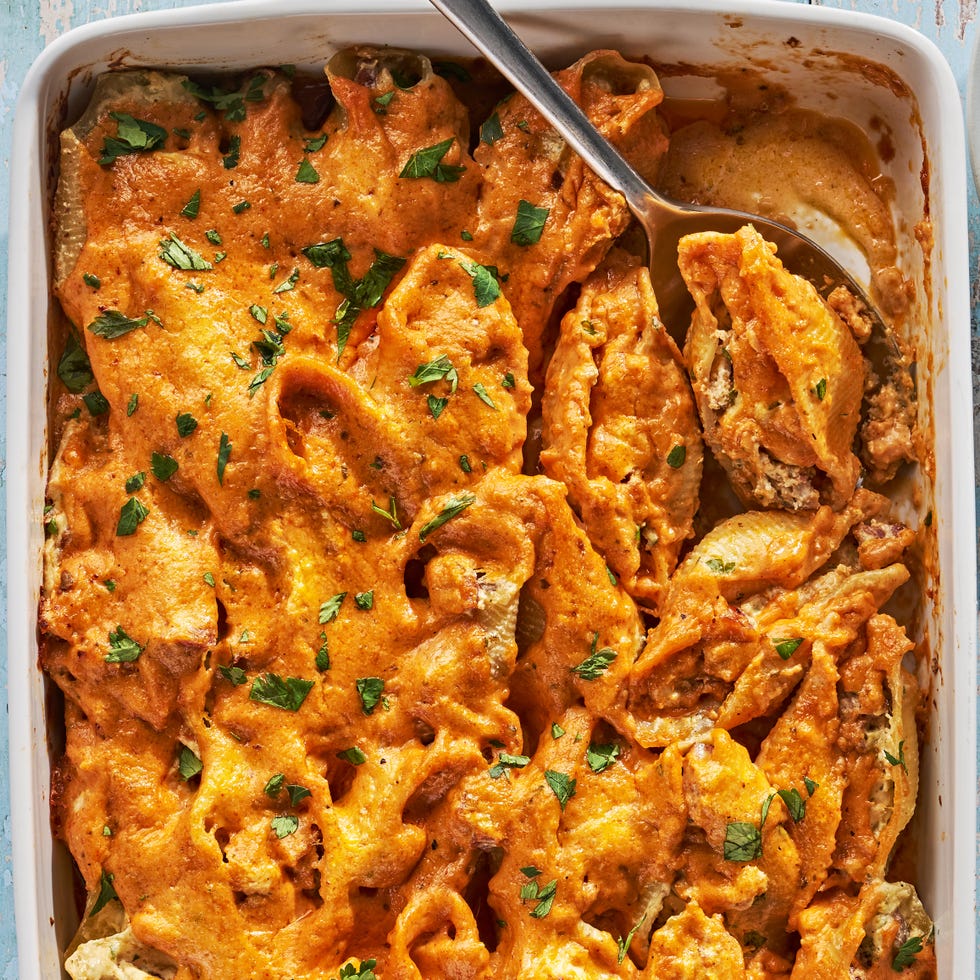 creamy cajun stuffed shells in a white baking dish on a blue wooden background