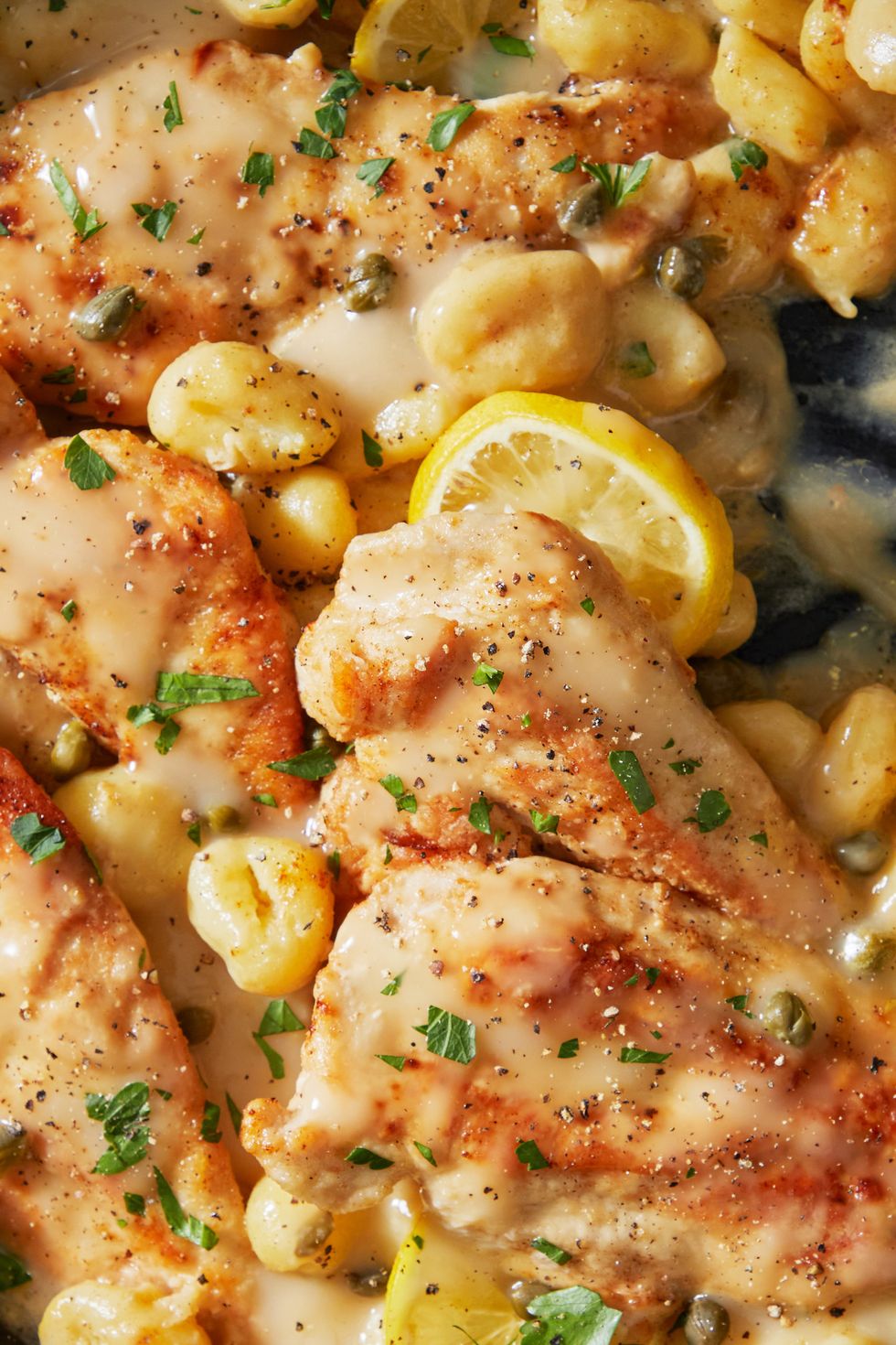 creamy chicken piccata with gnocchi in a pan with lemon