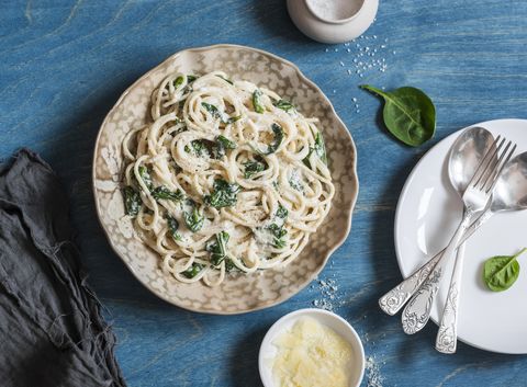 Creamy spinach spaghetti on blue wooden table, top view