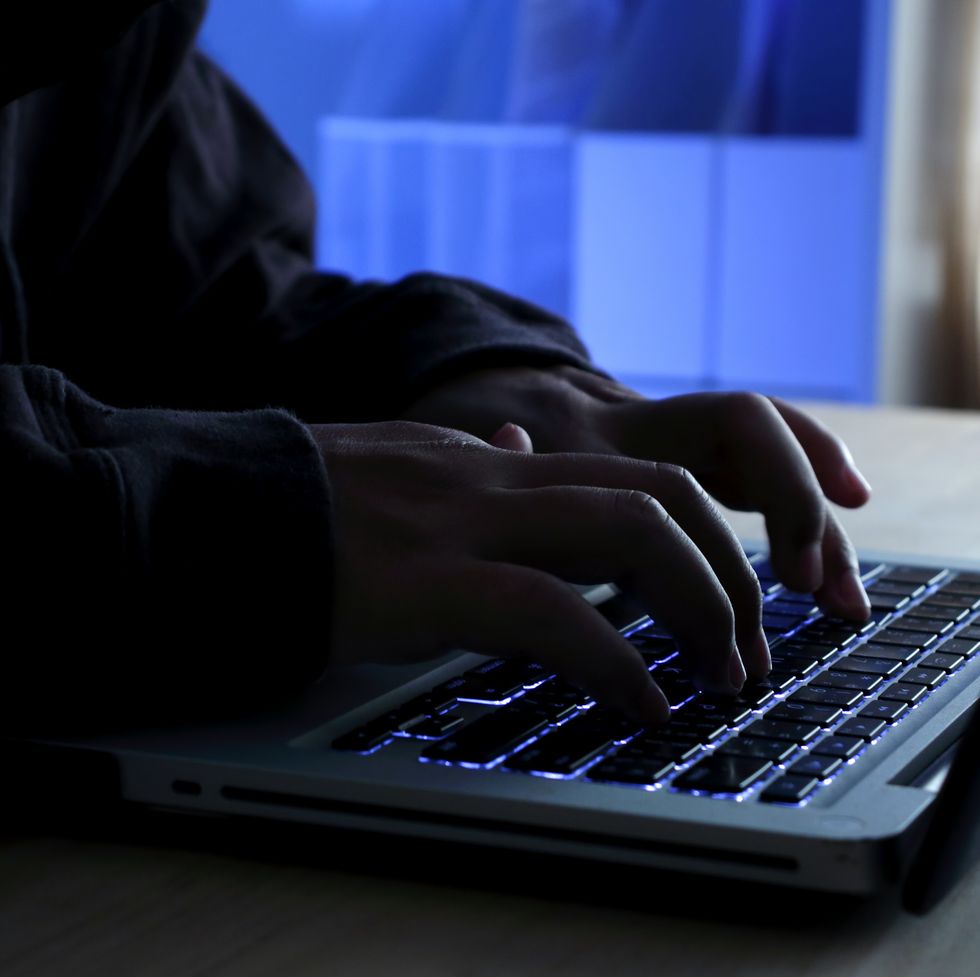 hacker working on laptop at night under blue light