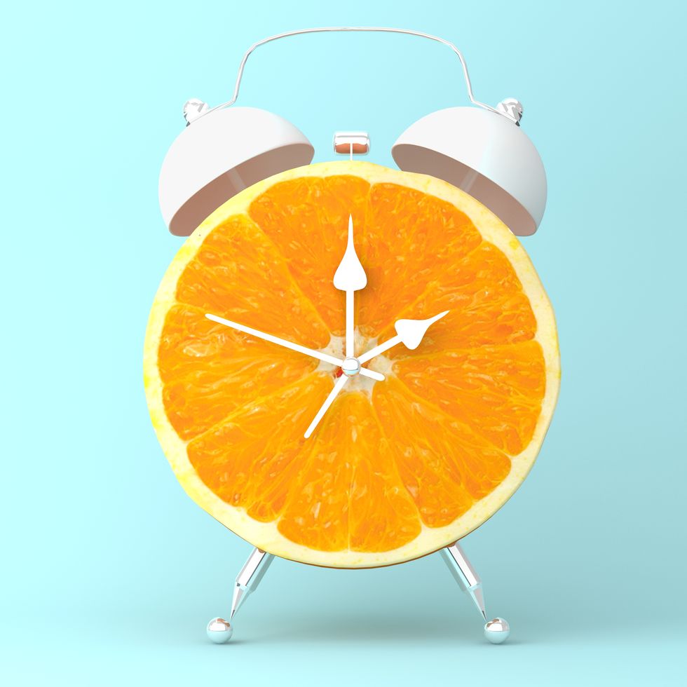 Creative idea layout fresh orange slice alarm clock on pastel blue background. minimal idea business concept. fruit idea creative to produce work within an advertising marketing communications