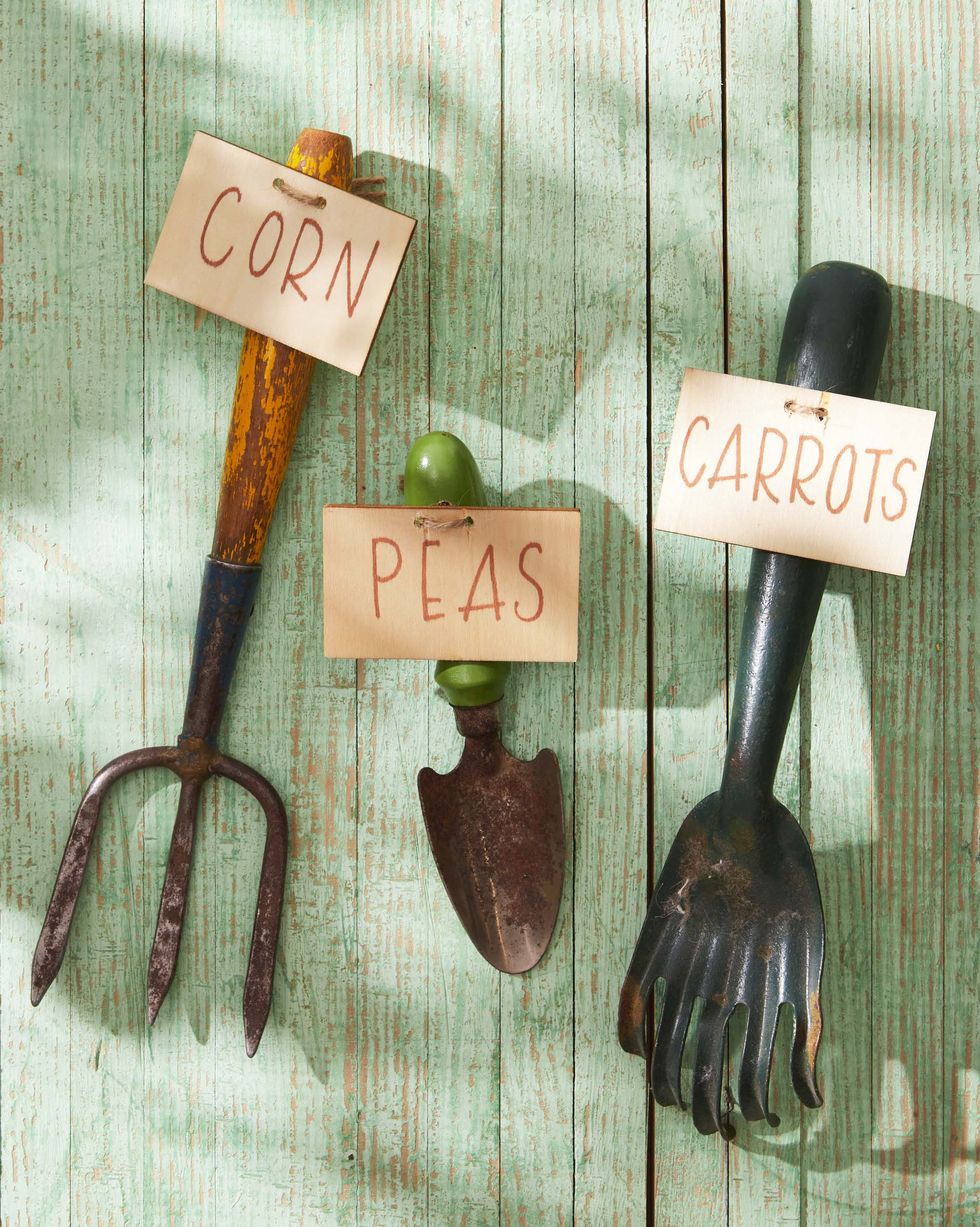 vintage garden tools turned into garden marker by attaching a wooden board with the name of the plantto the handle