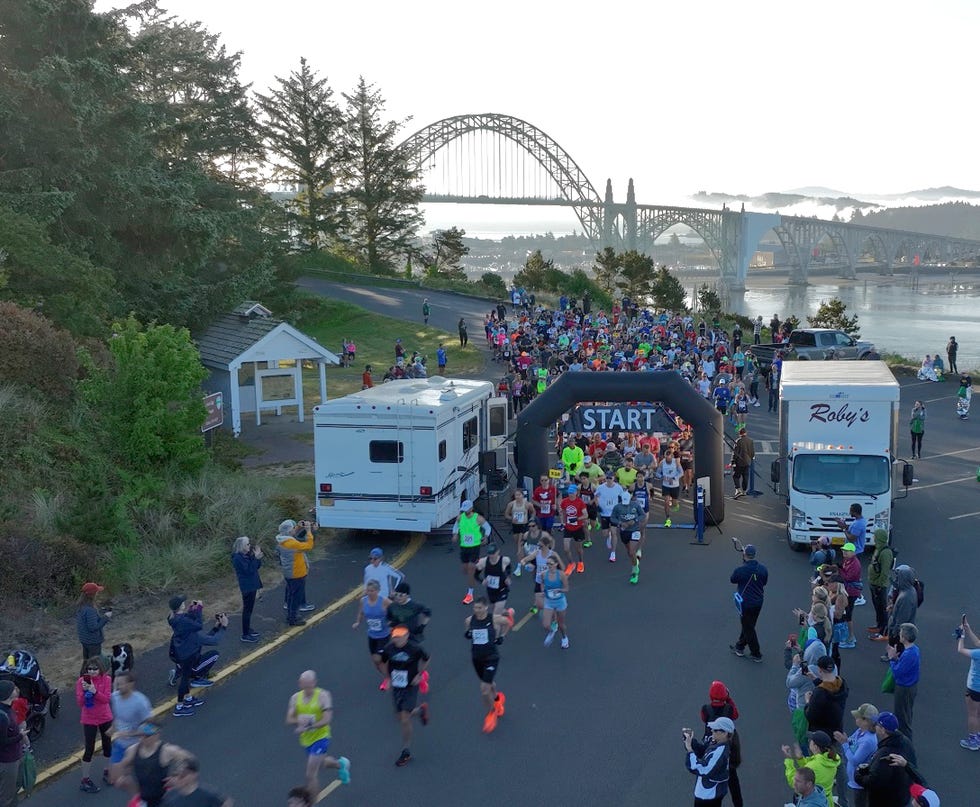 large group of runners starting a race near a bridge newport oregon marathon
