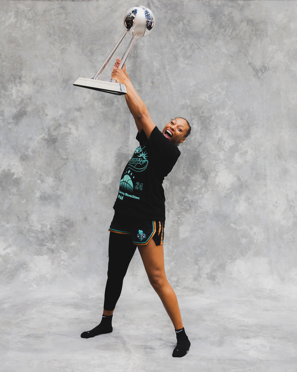 A person celebrating while holding a trophy aloft