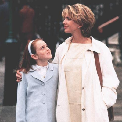 a woman and a young girl stand closely together on the street a woman and a young girl stand closely together on the street