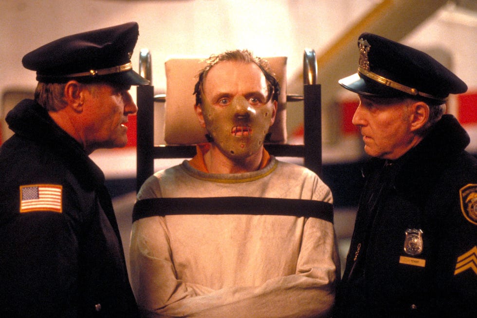 Individual restrained in a chair with police officers present Individual restrained in a chair with police officers present