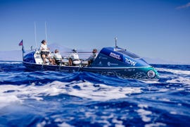 several people row a high tech row boat in ocean waves