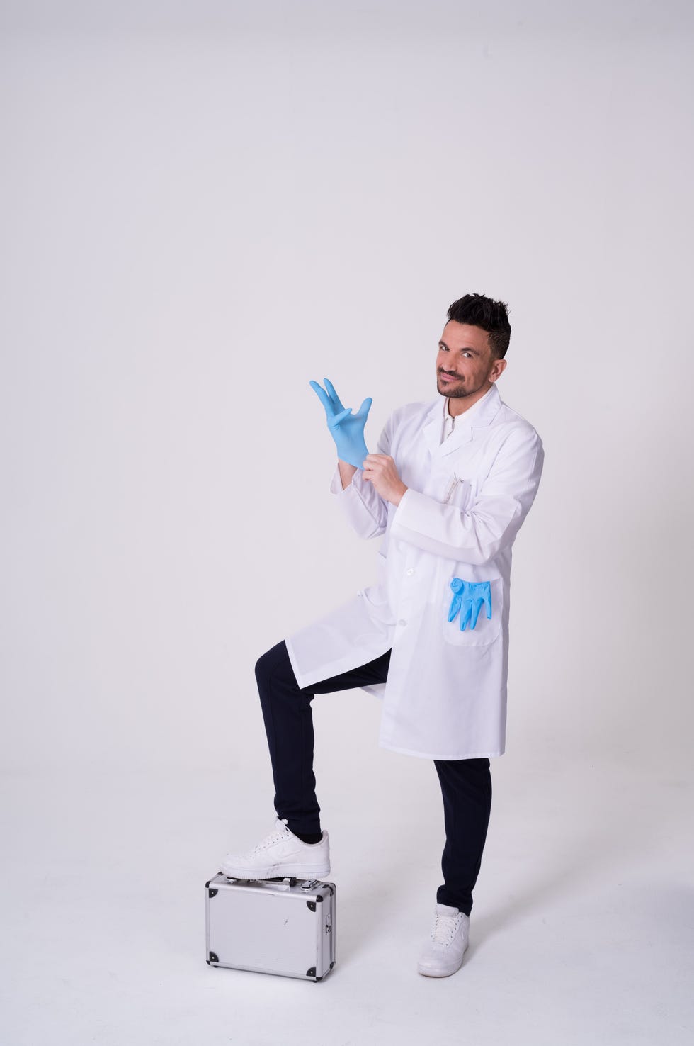 individual in a lab coat and gloves preparing for an activity