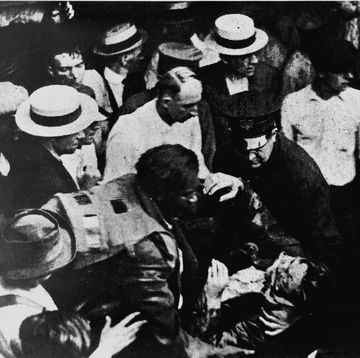 inventor garrett morgan helping responders lift the body of a tunnel disaster victim while wearing his safety hood device on his back