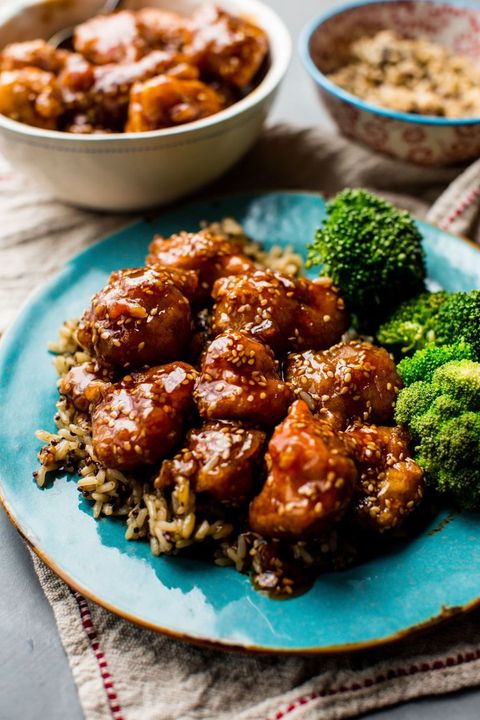 crispy honey sesame chicken with broccoli and brown rice on a teal plate
