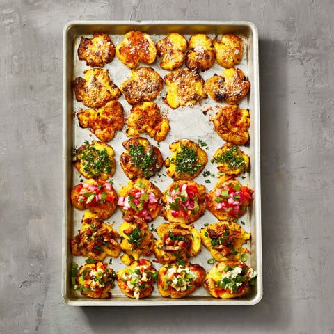 crispy roasted potatoes on a sheet pan with pico de gallo topping, bacon topping and fresh herb topping a green herby log of goat cheese on a white plate with slices of crusty toast
