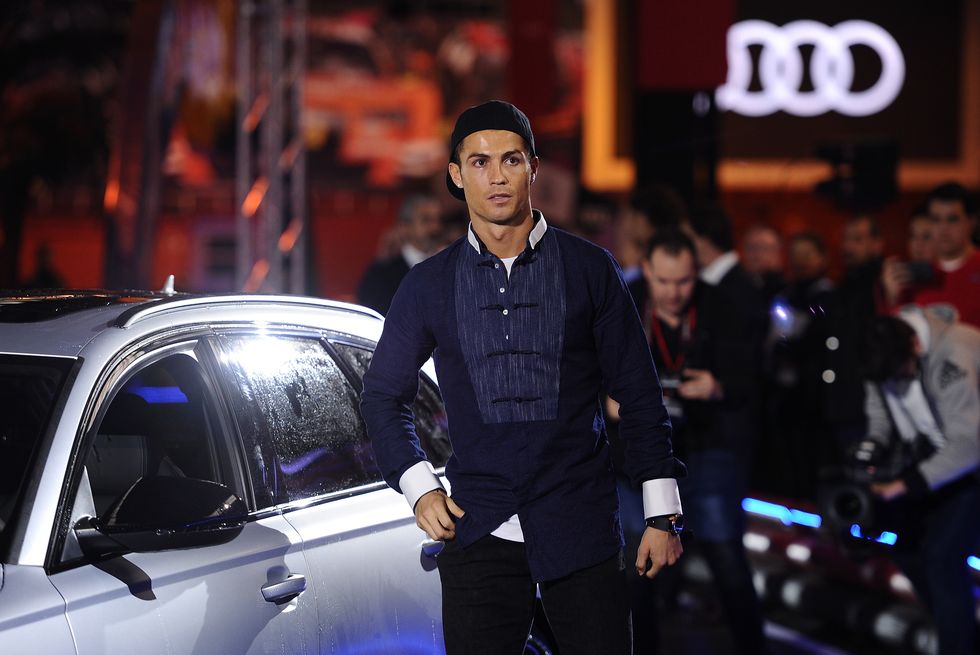 cristiano ronaldo fixing his suit next to an audi car at an event