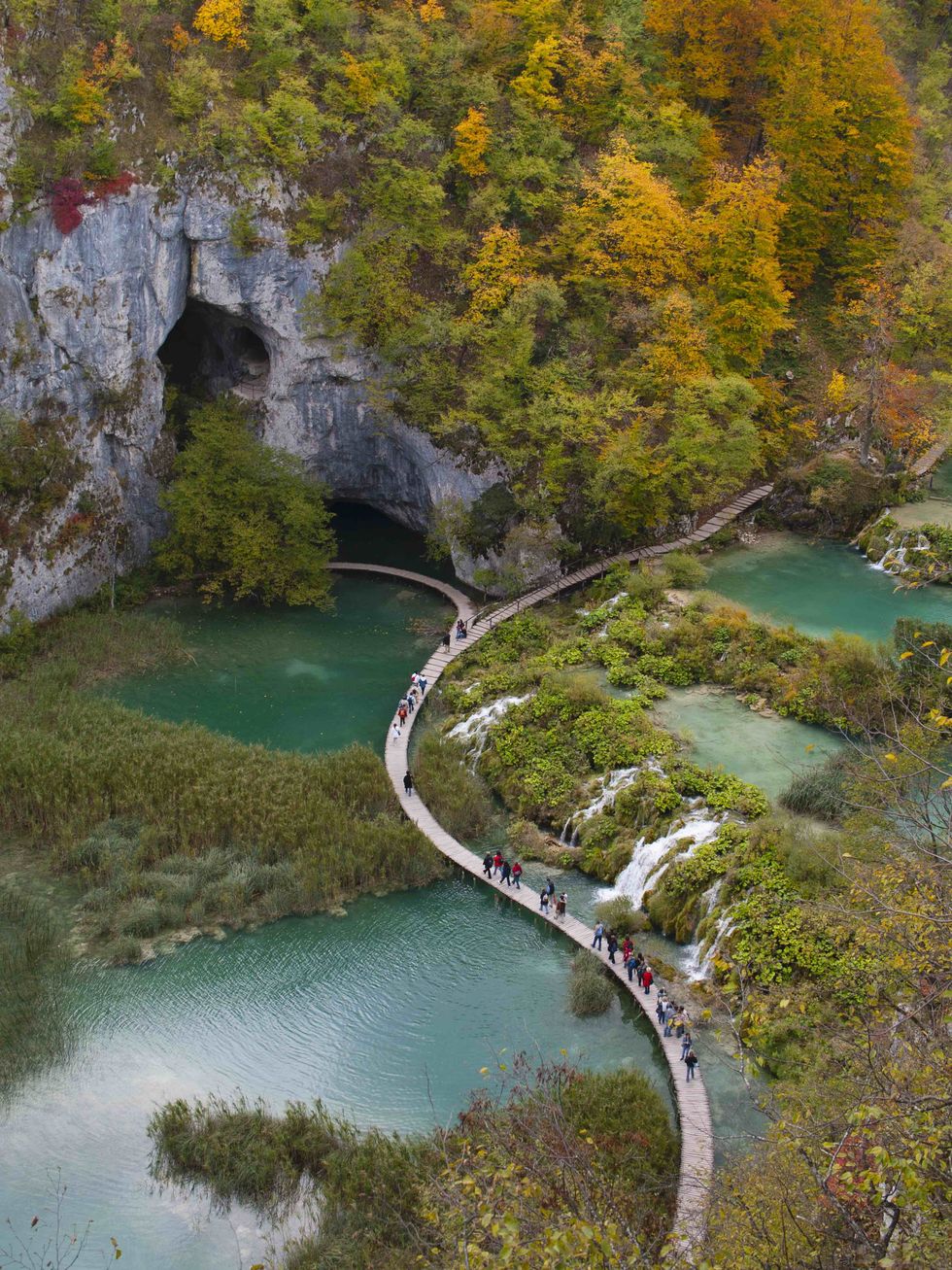 tourists walk on the main boardwalk in the centre of plitvice lakes national park during autumn the park was the first natural site to be included on unesco's world heritage list
