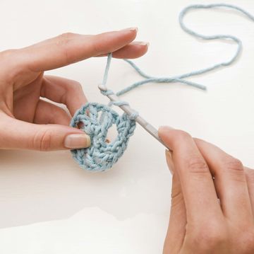 womans hands holding a crochet hook and yarn