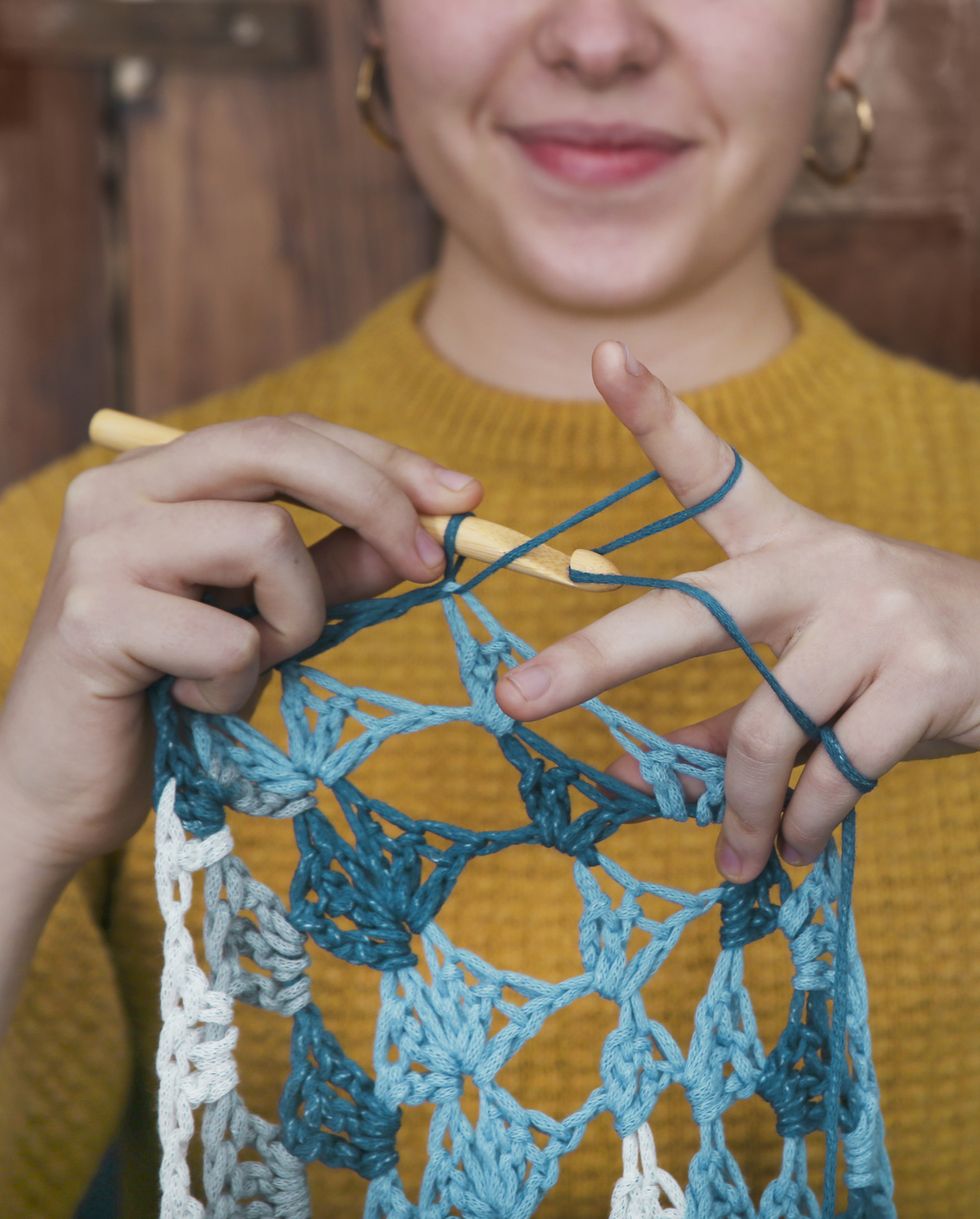 young woman crocheting doily closeup