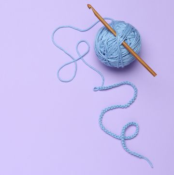 crochet hook and yarn on lilac background