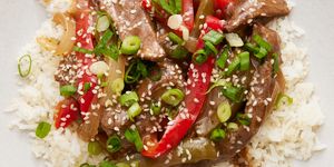 strips of flank steak with green and red peppers in a sauce served over white rice