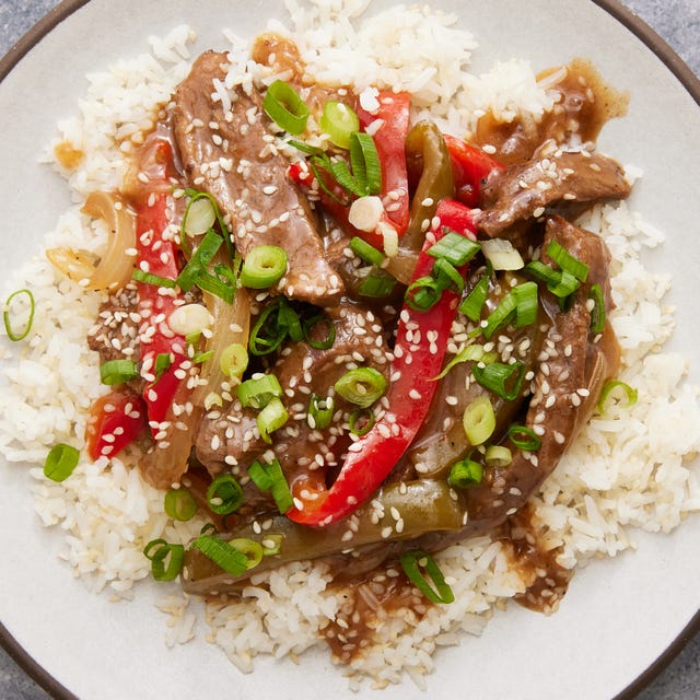 strips of flank steak with green and red peppers in a sauce served over white rice