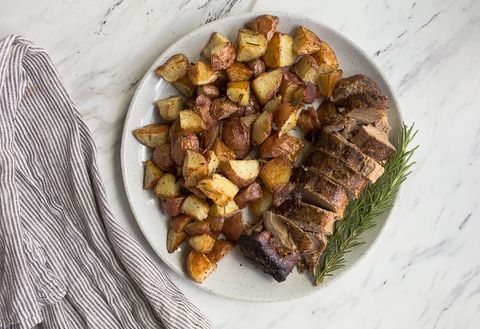 crock pot pork tenderloin on plate with potatoes and rosemary