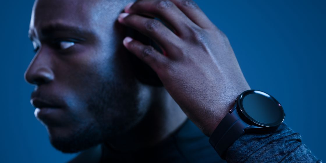 man adjusting headphones wearing a fitness watch