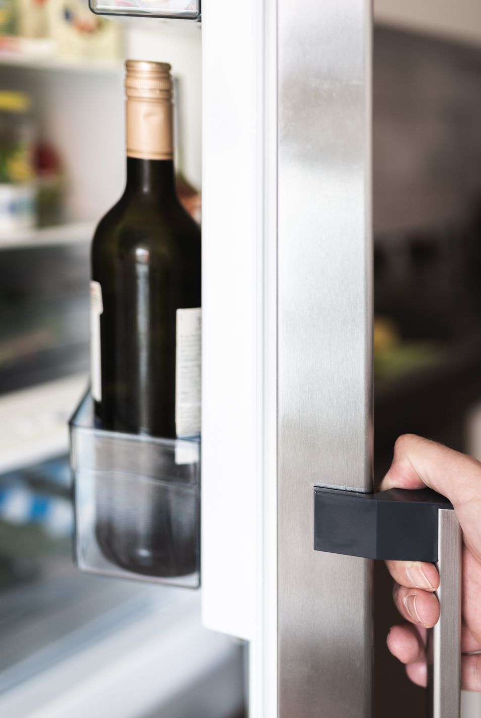 cropped hand holding refrigerator door