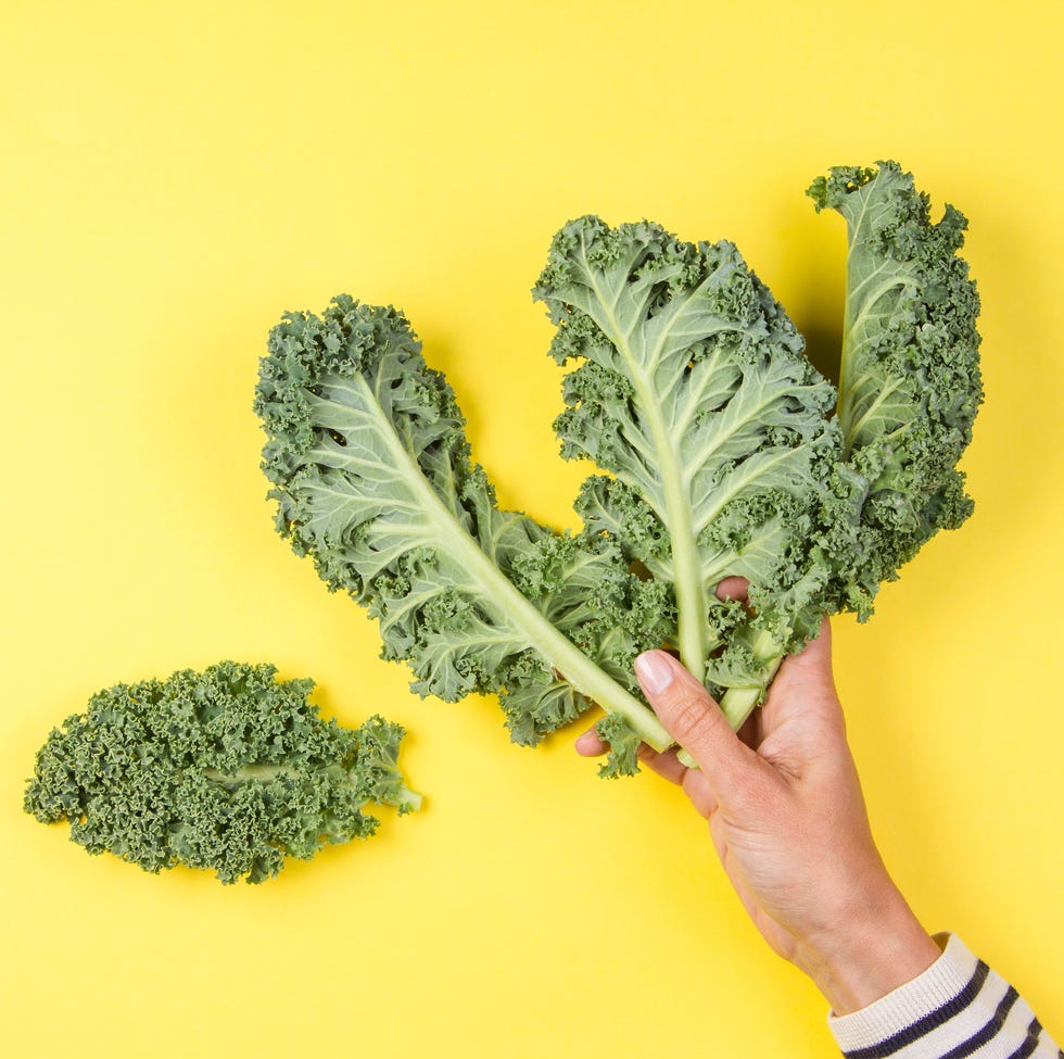 Cropped Hand Holding Vegetable Against Yellow Background