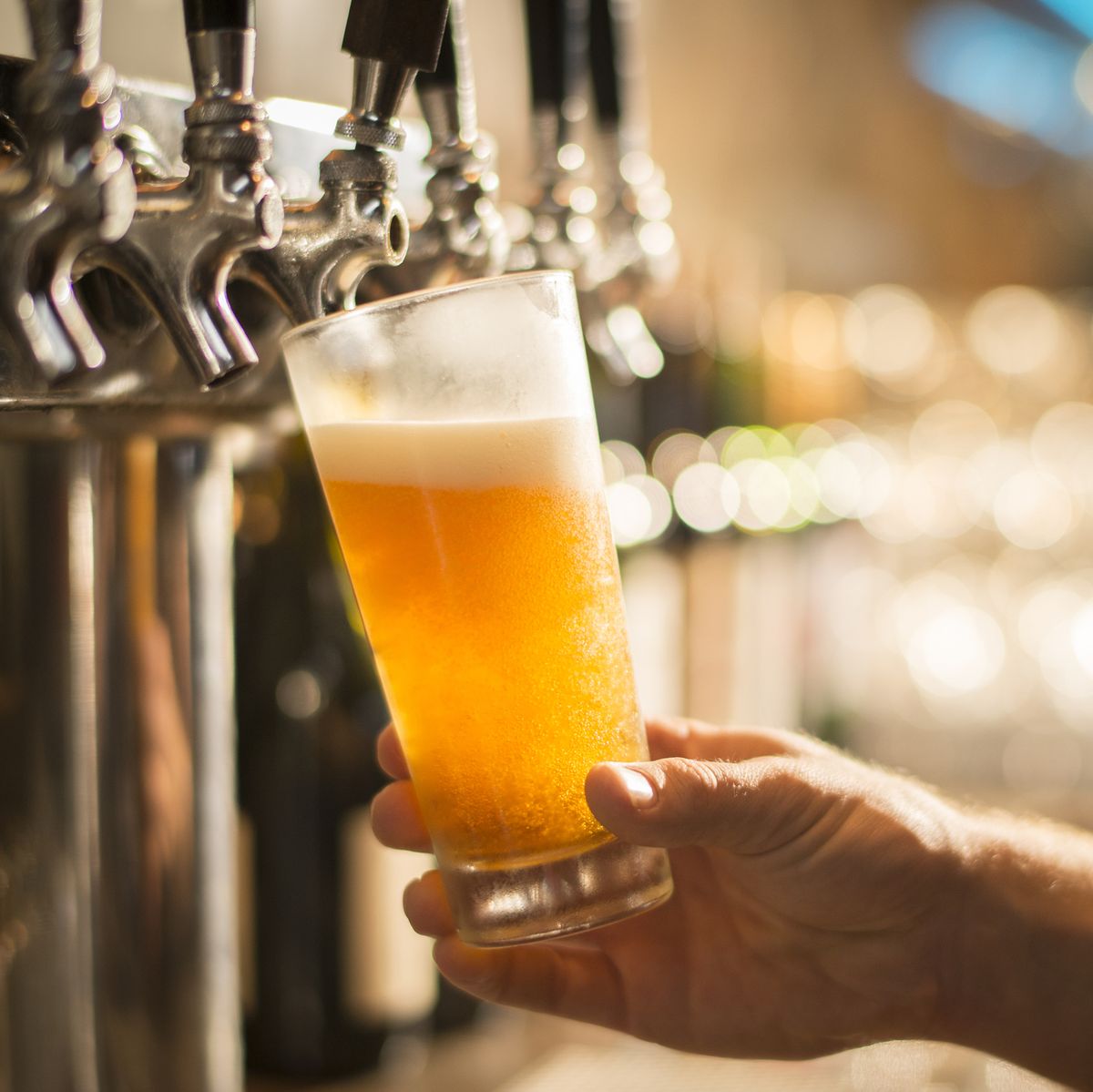 Cropped hand of bartender filling beer from tap at bar