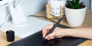 cropped hand of businesswoman using graphics tablet on desk