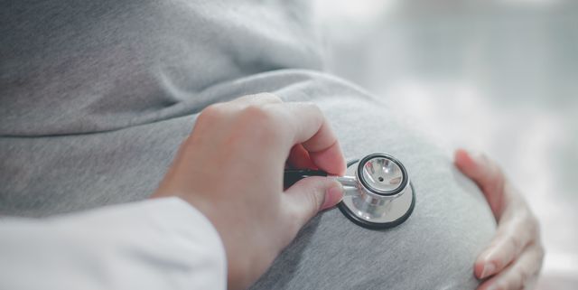 Cropped Hand Of Doctor Examining Pregnant Woman Belly With Stethoscope