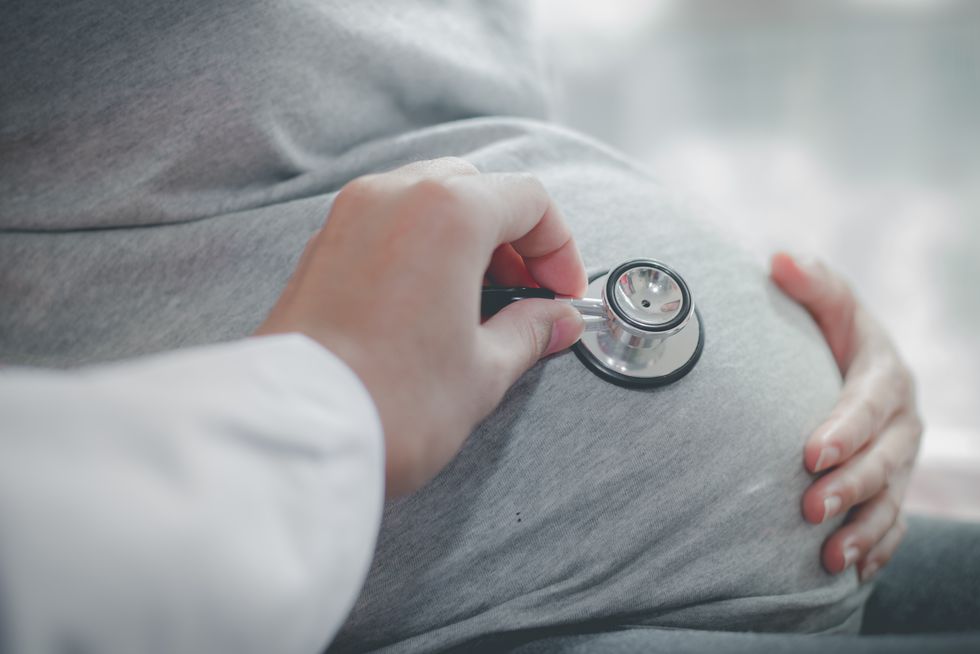 médico escuchando latido corazón del bebé de una mujer embarazada