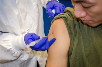 cropped hand of doctor injecting syringe on patient