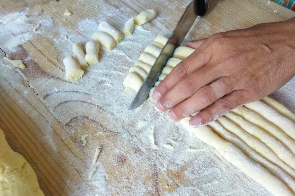 Cropped Hand Of Man Cutting Gnocchi On Table