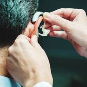 hearing aids over the counter cropped hand of person adjusting man hearing aid